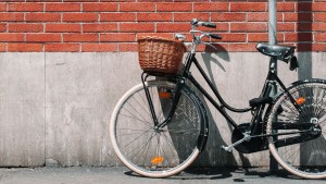 Een fiets met rietenmand die geparkeerd staat tegen een muur